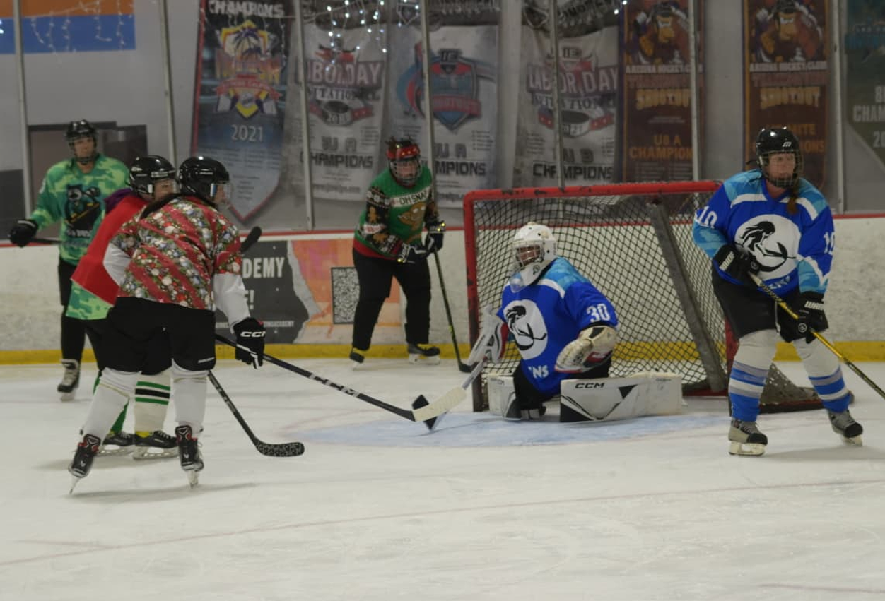 Players in a San Diego women's ice hockey game battling for the puck in front of the net.